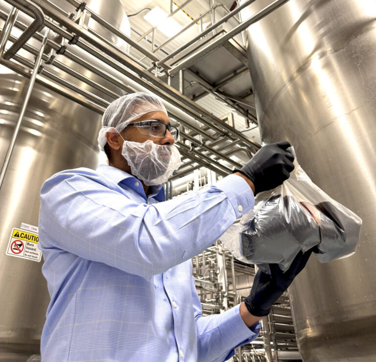 Universal Ingredients manager inspecting aseptic packaging with gloves and mask. clean facility